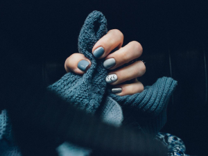 Painted fingernails gripping scarf in dark surroundings