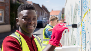 Young smiling volunteers painting a mural